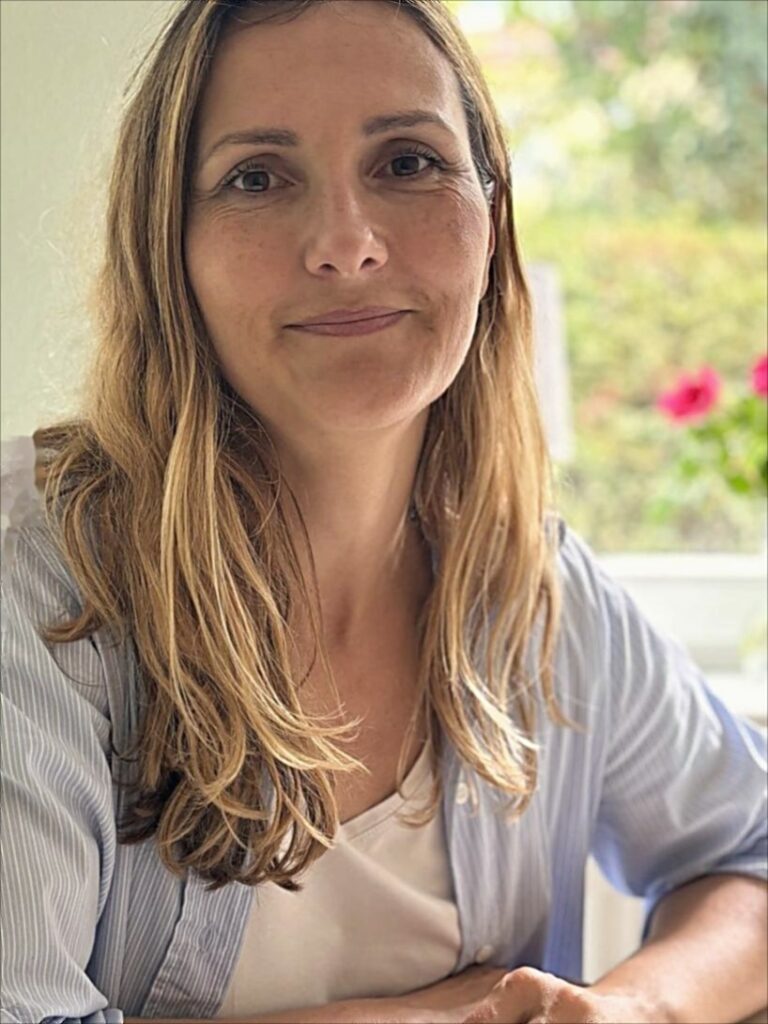 Anja Feierabend, Heilpraktikerin in Kronberg, lächelt am Tisch ihrer Naturheilpraxis