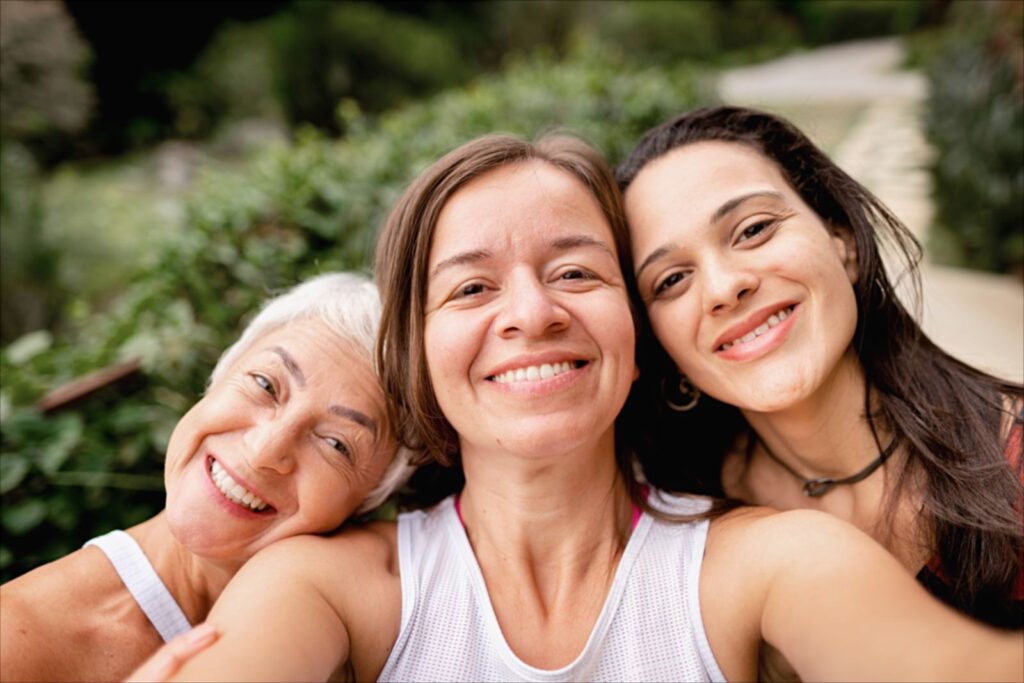 Drei Frauen unterschiedlichen Alters lachen gemeinsam in die Kamera