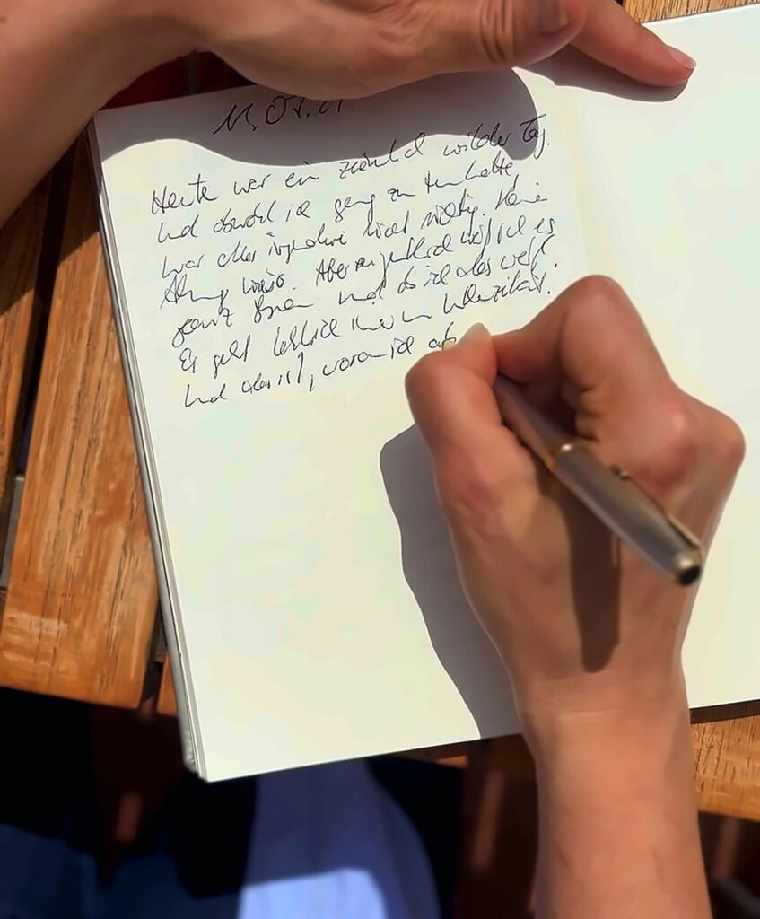 Hand schreibt Gedanken in ein Notizbuch, Symbol für Glaubenssatzarbeit