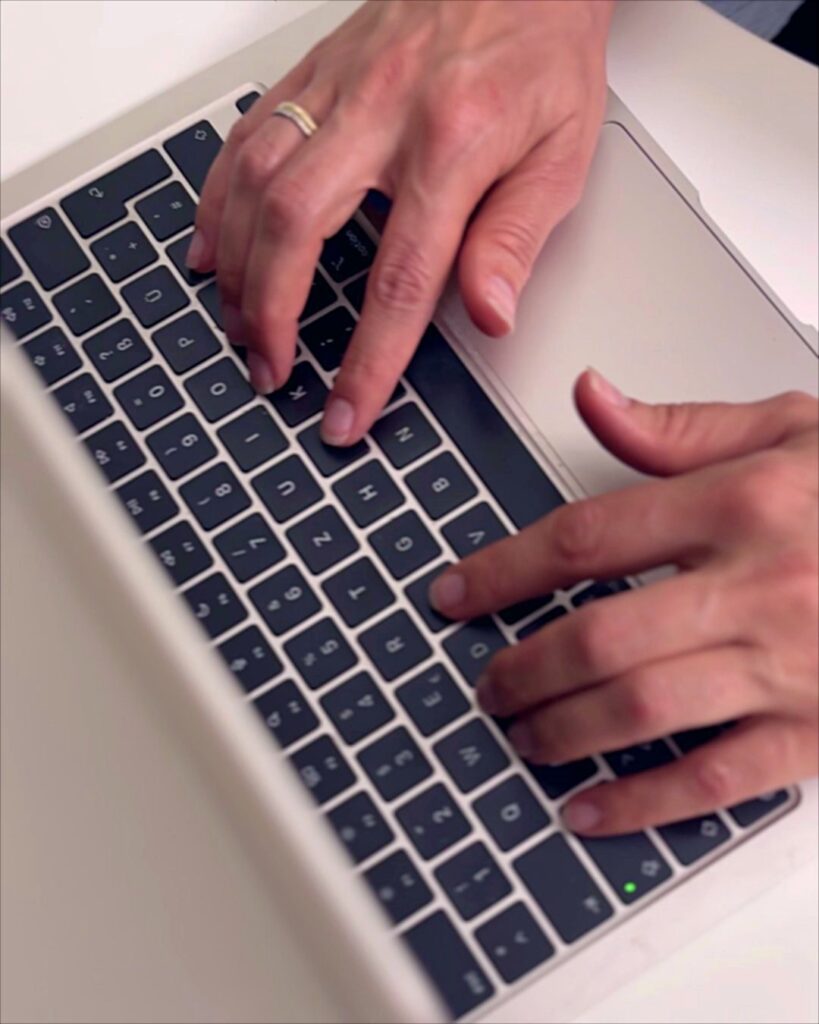 Hände von Anja Feierabend tippen auf der Tastatur eines Laptops